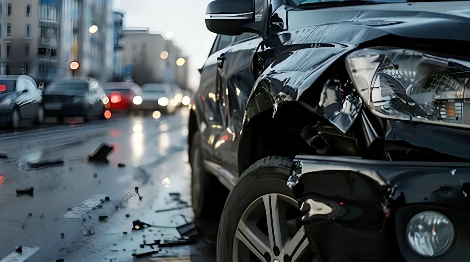 KFZ-Sachverständigenbüro - Peter Kühn - Ein schwarzer Wagen mit einer völlig zerstörten Frontpartie steht im Regen.